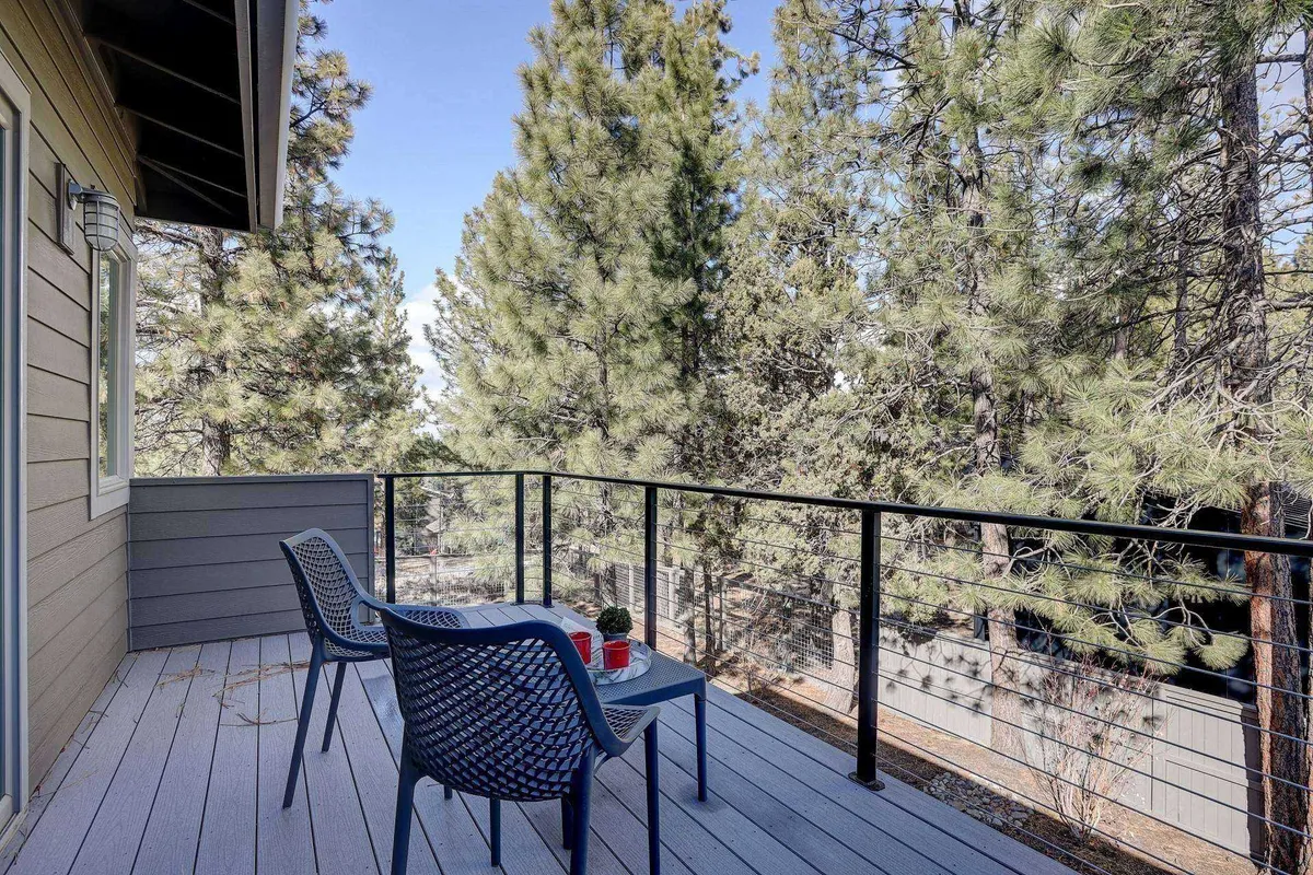 Two comfortable chairs and a small table are placed in a serene, tree-lined outdoor space, offering a peaceful spot for morning coffee or an evening recap under the stars.