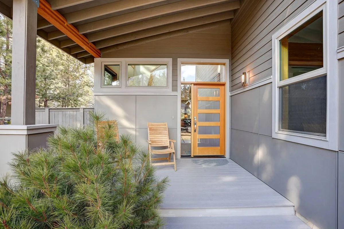 This image shows the exterior front entry of the property, with a welcoming front door, wooden chairs for relaxing, and well-maintained landscaping. The scene exudes tranquility and hints at the inviting comfort that awaits after a day out exploring or golfing nearby.